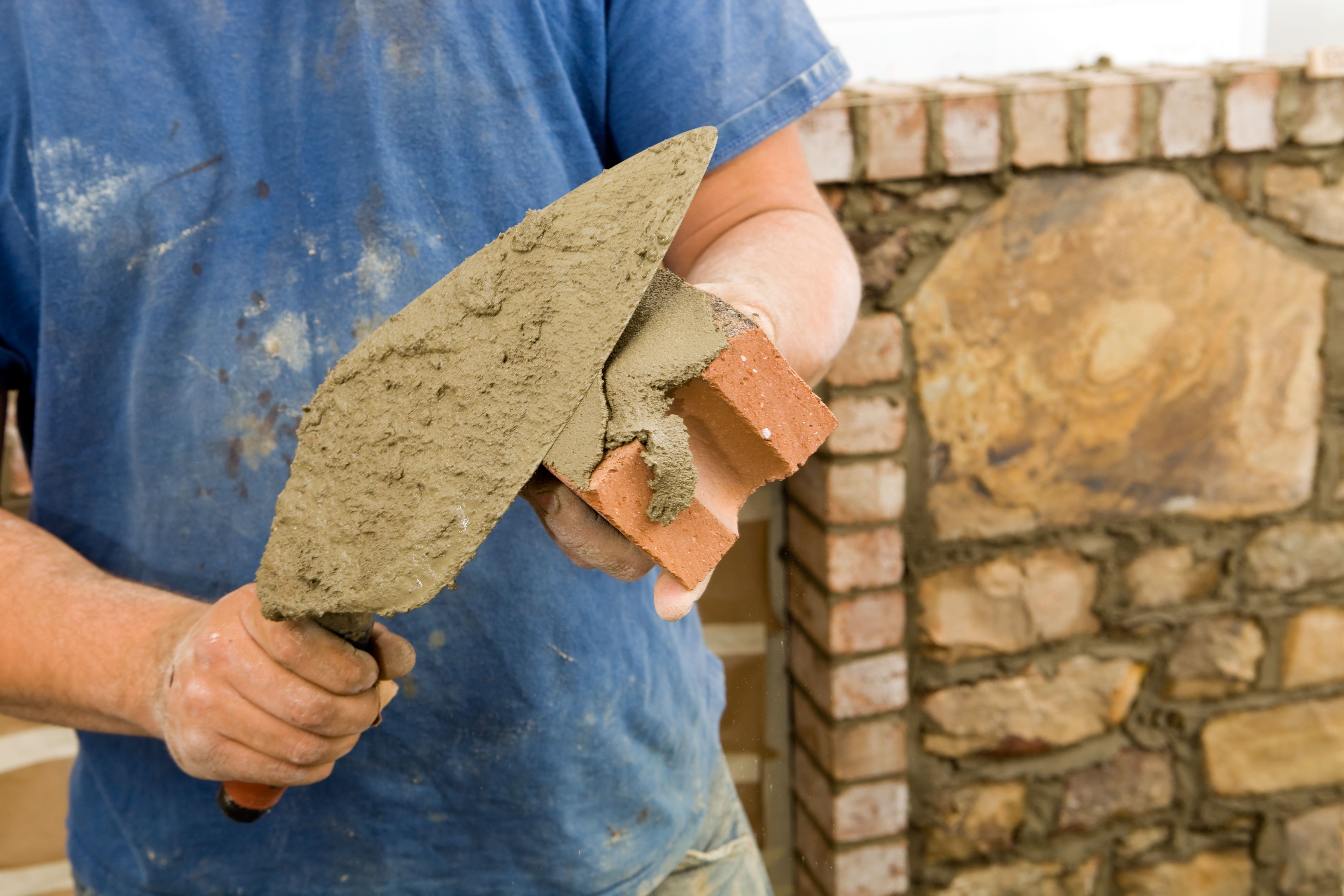 man trowling mortor onto brick